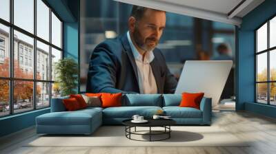 A smart, professional CEO sitting at his desk, working on a laptop in a modern office at night. Wall mural