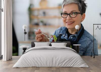 Adult smiling woman holding a plate with fresh salad, diet lunch. Wall mural