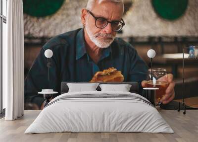 An adult man is having lunch in a pub. Eating a burger with beer. Wall mural