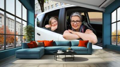 Cheerful woman and girl look out the car window. Wall mural