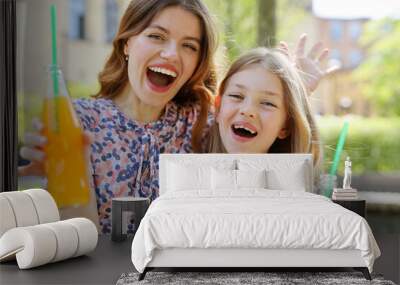 Happy woman and little girl with soda in their hands on a summer day. Wall mural