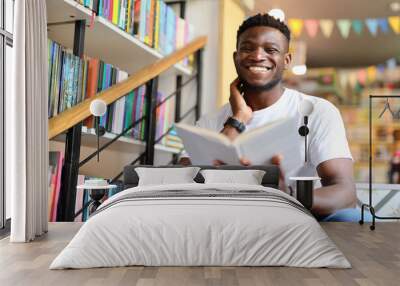 Happy young student in a library, surrounded by books and knowledge, exuding academic joy. Wall mural