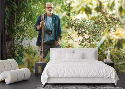 Retired and active, walking along the trail in the forest. Gray-haired man with a beard on vacation. Wall mural