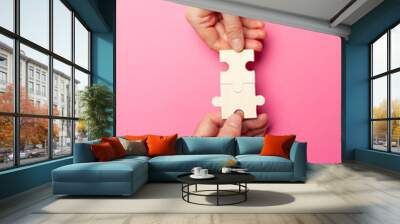 Two hands connect puzzles on a pink background. Cooperation and teamwork in business. Collaboration people for success. Wall mural