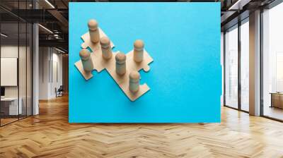 Wooden figures on puzzles on blue background as a symbol of team building. Organization group people in business. Cooperation and partnership. Wall mural