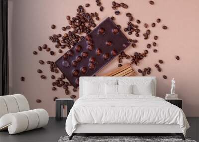 Chocolate bar with nuts on the beige background with coffee beans and spices. Roasted coffee beans, cinnamon sticks and anise stars. Chocolate bar with hazelnuts. Top view. Wall mural