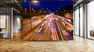 Long exposure above high angle aerial view of Aleja Armii Ludowej street in Warsaw, Poland at night with traffic cars, people standing at bus stop with light trails Wall mural