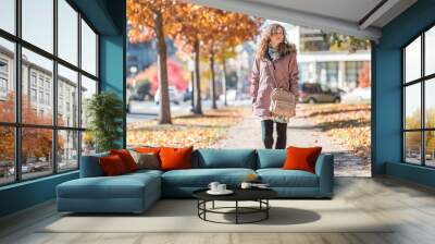 Young happy woman walking on sidewalk street in Washington DC, USA United States legs in alley of golden orange yellow foliage autumn fall trees on road during sunny day Wall mural