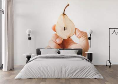 Hand holding a sliced pear on a white background. Copy, empty space for text Wall mural