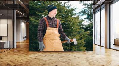 Man lumberjack with an ax in his hands on a background of forest and trees Wall mural