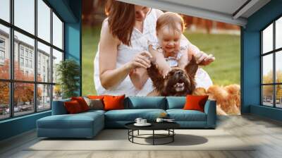 family in nature for the weekend. young beautiful mother and child girl are playing and having fun with domestic dog on backyard green grass on summer sunny day. Mothers day, baby day Wall mural