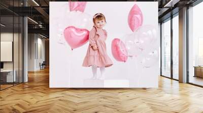 happy birthday 2 years old little girl in pink dress. white cake with candles and roses. Birthday decorations with white and pink color balloons and confetti for party on a white wall. Happy birthday Wall mural