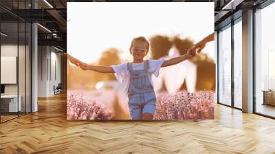 Mother, father hold hands of happy daughter enjoy nature and walk in the lavender field on sunset. View down the legs. Young family spending time together on vacation, outdoors. summer holiday. Wall mural