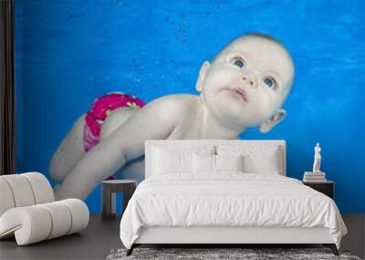 Beautiful baby girl swim underwater on blue water background. Healthy family lifestyle and children water sports activity. Child development, disease prevention Wall mural