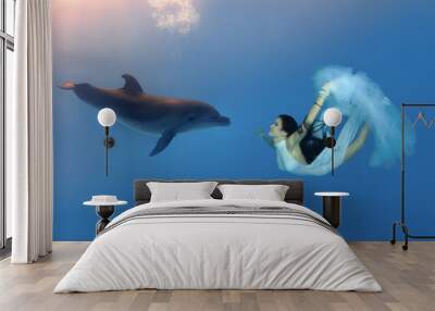 Bride in a wedding white dress with a veil swims to meet a dolphin. Underwater wedding Wall mural