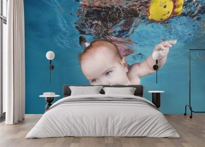 Cute chubby little girl plays with toy underwater in a swimming pool Wall mural