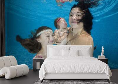 Mom and two daughters posing under water in pool Wall mural