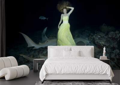 Night dance with sharks. Young beautiful woman in yellow dress dancing underwater with Tawny Nurse Sharks (Nebrius ferrugineus), night shooting in Indian Ocean on Maldives Wall mural