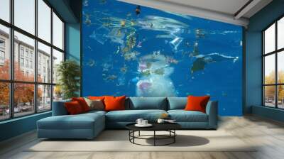 Plastic and other debris floats underwater in blue water. Plastic garbage polluting seas and ocean Wall mural