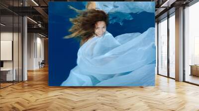 Young beautiful woman with long hair in a long white dress under water, underwater fashion in the pool  Wall mural