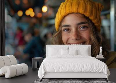 A young woman in a yellow beanie smiling while enjoying a relaxed moment at a food truck, offering a cozy, cheerful scene with tasty street food and a bustling background. Wall mural