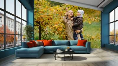 Mom and son walking and having fun together in the autumn park. Wall mural