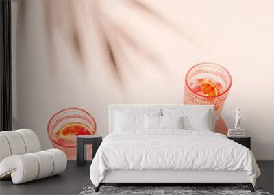 Creative composition made of two glasse with cocktail or lemonade on beige pastel background with lobule of bloody orange. Summer refreshment concept. Sunlit flat lay. Minimal style. Top view Wall mural