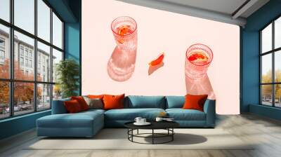 Creative composition made of two glasse with cocktail or lemonade on beige pastel background with lobule of bloody orange. Summer refreshment concept. Sunlit flat lay. Minimal style. Top view Wall mural