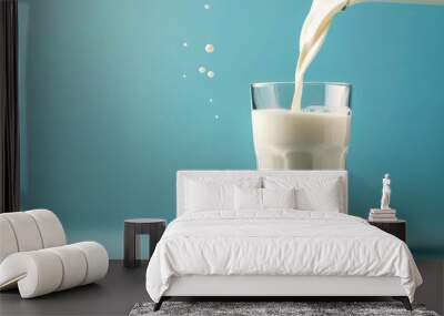 Pouring organic milk in glass on blue background Wall mural