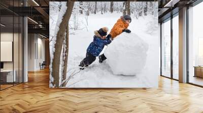 boys ride a big snowball in a winter forest Wall mural