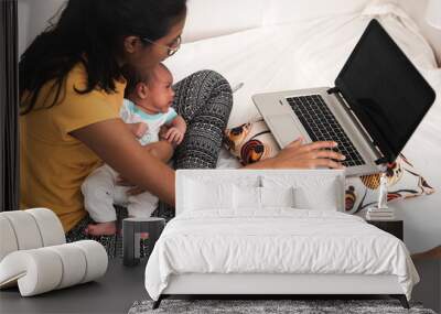 Young Hispanic mother with a baby working from home Wall mural