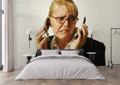 business woman expresses stress as she shuffles two cell phones. Wall mural