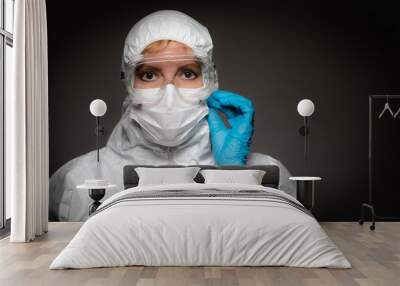 Female Medical Worker Wearing Protective Face Mask and Gear Against Dark Background Wall mural