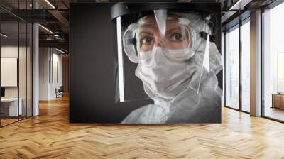 Female Medical Worker Wearing Protective Face Mask and Gear Against Dark Background Wall mural