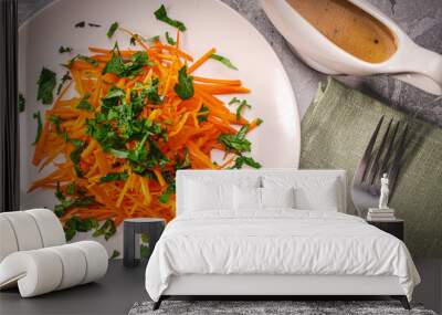 Carrots and parsley, finely thinly sliced on a white plate on a gray background with a fork on a green napkin. Dietary Nutrition Concept Wall mural