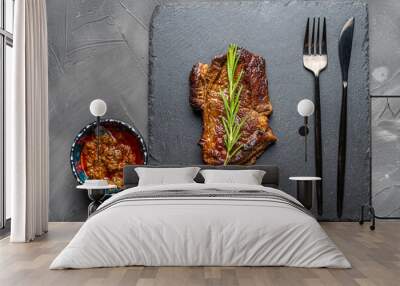 Grilled Marbled Beef Steak with a sprig of rosemary on a mica board with sauce and Argentinian Chimichurri sauce in a bowl on a dark background Wall mural