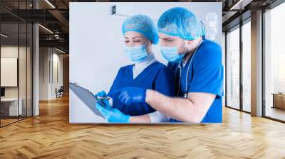 The male surgeon explains to the female anesthesiologist. And she makes notes on the tablet. Medicine concept. Operating room. Wall mural