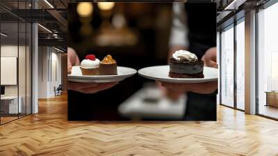 Close-up of a person holding two desserts, one with whipped cream and the other with a raspberry topping, on white plates. Wall mural