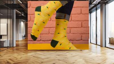 female legs in yellow socks with drawings of lemon, on a yellow surface, concept Wall mural