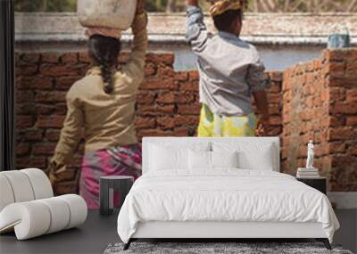 two Indian women in traditional dress work at a construction site with jugs on their heads, hard work Wall mural