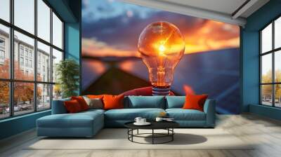 hand holding glowing light bulb with a house green power plant of solar panels on roof at background.	 Wall mural