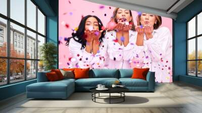 Blowing confetti, friends and women in studio for party celebration, fashion sale and discount. Bonding, diversity and happy people on pink background for support, natural beauty and retail promotion Wall mural