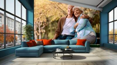 Senior couple, park bench and happy while sitting together in retirement for freedom, peace and calm with a smile and happiness in nature. Old man and woman outdoor to relax while on vacation Wall mural