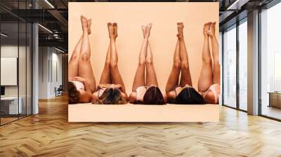 Skincare, diversity and legs of women in studio for care, comparison and wellness on wall background. Difference, beauty and female friends relax in a line with feet up for glowing skin or treatment Wall mural