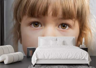 Emotional portrait of a 4-year-old girl with ponytails on her head against a light background, close-up. Wall mural