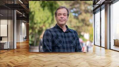 Portrait of a confident man of 45-50 years old on a neutral blurred background of a city park. Wall mural