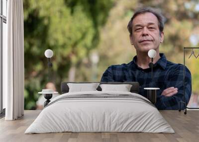 Portrait of an older and confident 50-55 year old man wearing a shirt on a neutral urban background, looking into the camera, space for text, copy space. Wall mural