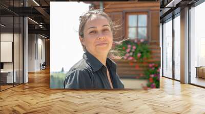 Street portrait of a dark-haired joyful woman 40-45 years old on the background of a wooden house with flowers. Wall mural