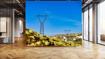 Power line voltage tower in mountains against blue sky Wall mural