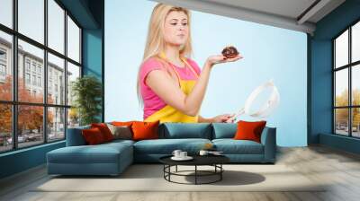 Woman holding chocolate cupcake and colander Wall mural